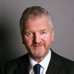 Ralph Lucas, short light brown/grey hair, beard and moustache, smiling, wearing dark suit and tie