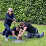 Melissa Briggs, in garden with two men, installing ground equipment