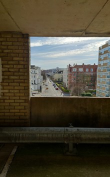 A view from inside a concrete car park, looking out onto tall buildings